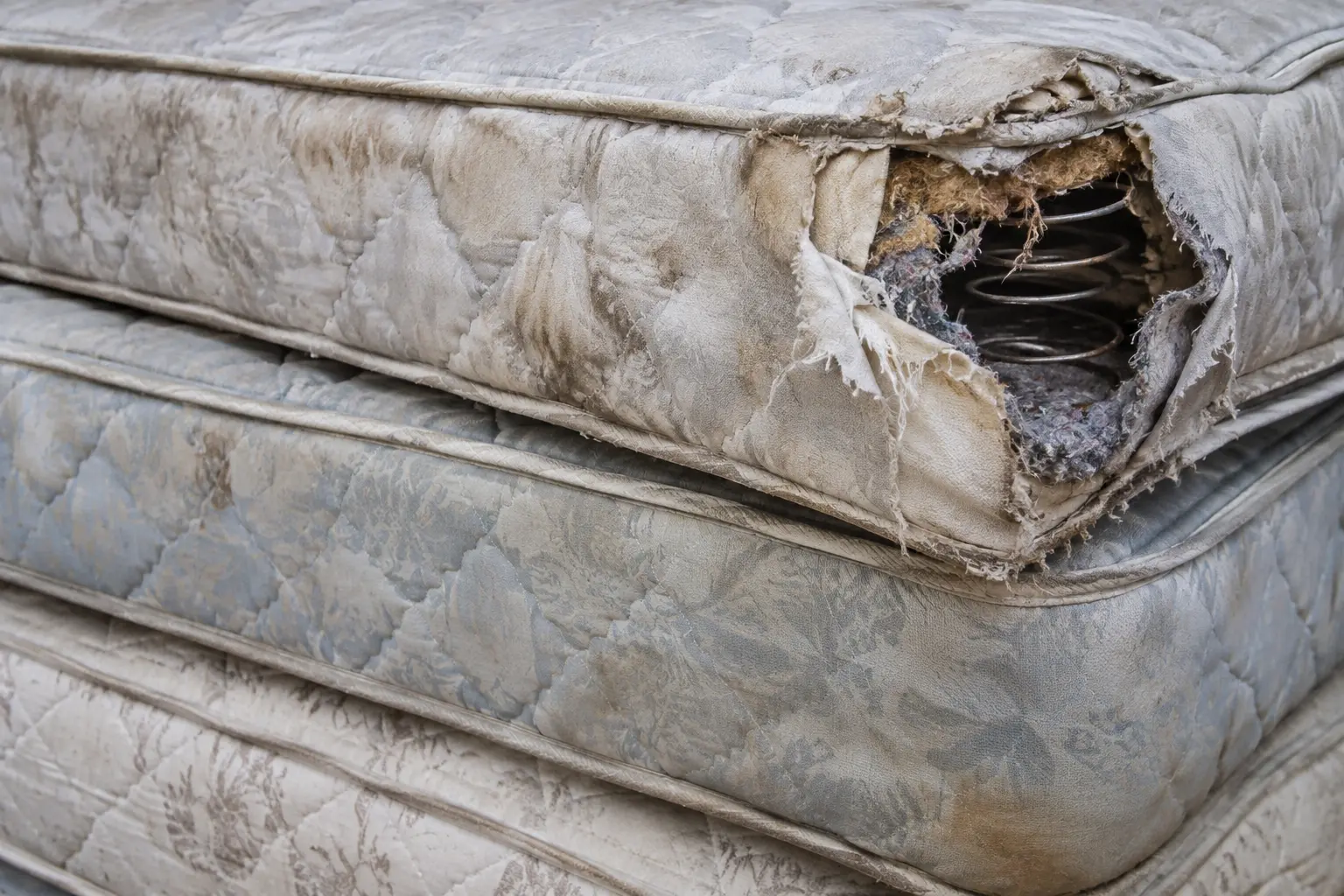 Illustrative close-up of old mattresses with a torn cover and exposed springs